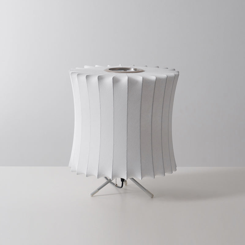 Waisted white Clérachic table lamp, unlit, seen from a slightly higher angle on a grey set, with a pleated top edge.