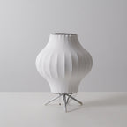 Unlit pear-shaped white Clérachic table lamp on a pale grey set, with a pull chain hanging between its tripod legs.
