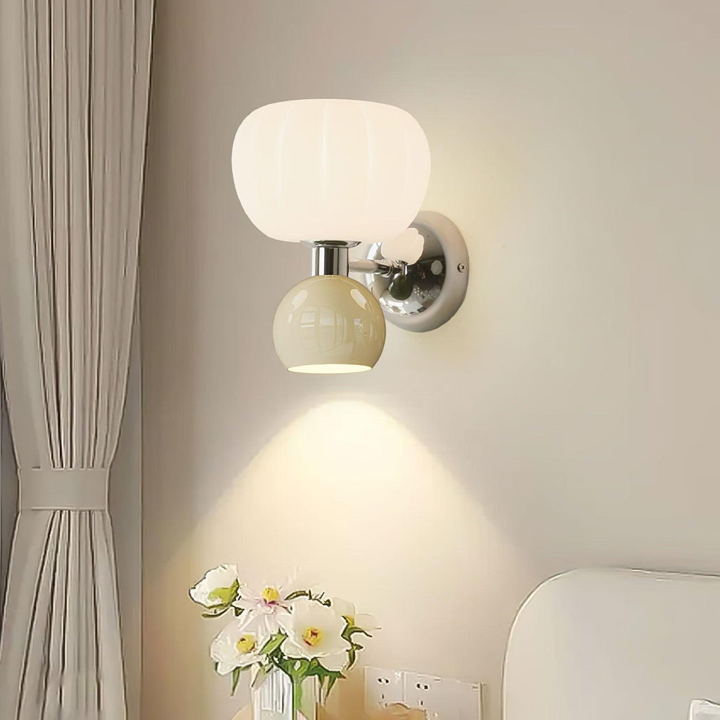 Close view of this Clérachic chrome wall sconce with a pale sage-grey ball, its downward beam falling on the wall above a vase of white flowers.