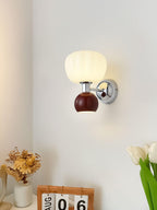 Beside a flip calendar and green tulips, this Clérachic chrome wall light with a deep red ball and ribbed glass shade is lit on a white wall.