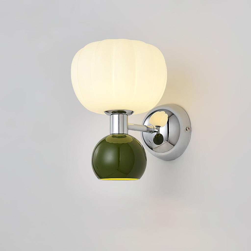 Close view of the dark green ball and chrome arm on this Clérachic wall light, with its ribbed glass shade lit warm white.