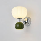 Close view of the dark green ball and chrome arm on this Clérachic wall light, with its ribbed glass shade lit warm white.