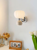 This Clérachic chrome wall light with a cream ball hangs above a desk with a flip calendar, dried flowers and white tulips.