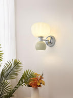 Lit next to a palm frond and a vase of orange flowers, this Clérachic chrome wall light has a pale sage-grey ball and a ribbed shade.