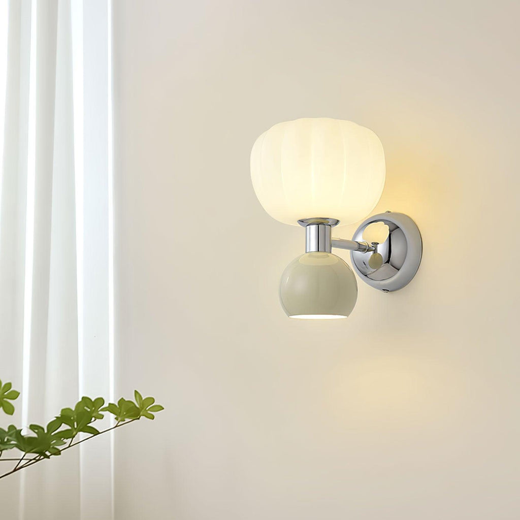 This Clérachic chrome wall light with a pale sage-grey ball glows next to a sheer white curtain and a green branch.