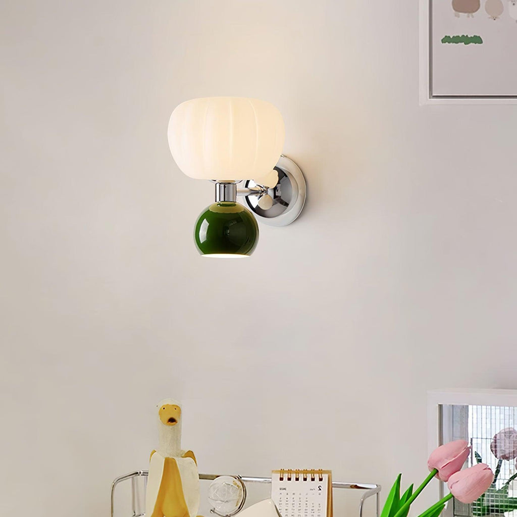 This Clérachic chrome wall light with a dark green ball is lit on a pale wall above a desk with a pink tulip bunch and a small print.