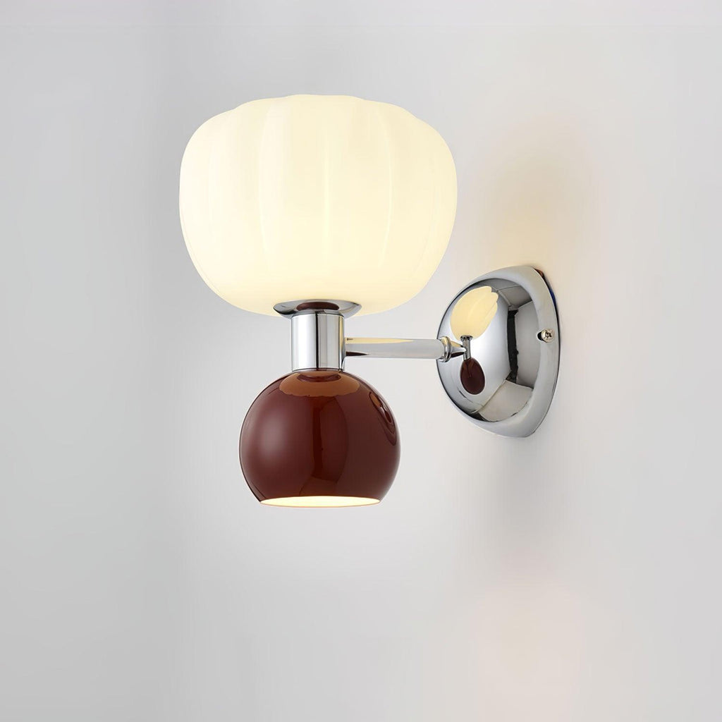Close view of this Clérachic chrome wall light with a deep red ball and a glossy chrome arm and back plate against a grey wall.