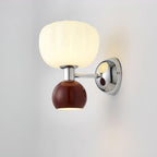 Close view of this Clérachic chrome wall light with a deep red ball and a glossy chrome arm and back plate against a grey wall.