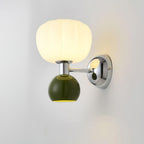 Close view of this Clérachic chrome wall light with a dark green ball under a ribbed glass shade, lit on a pale wall.