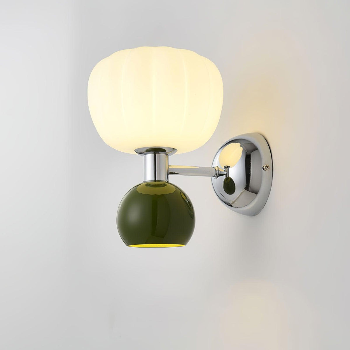Close view of this Clérachic chrome wall light with a dark green ball under a ribbed glass shade, lit on a pale wall.