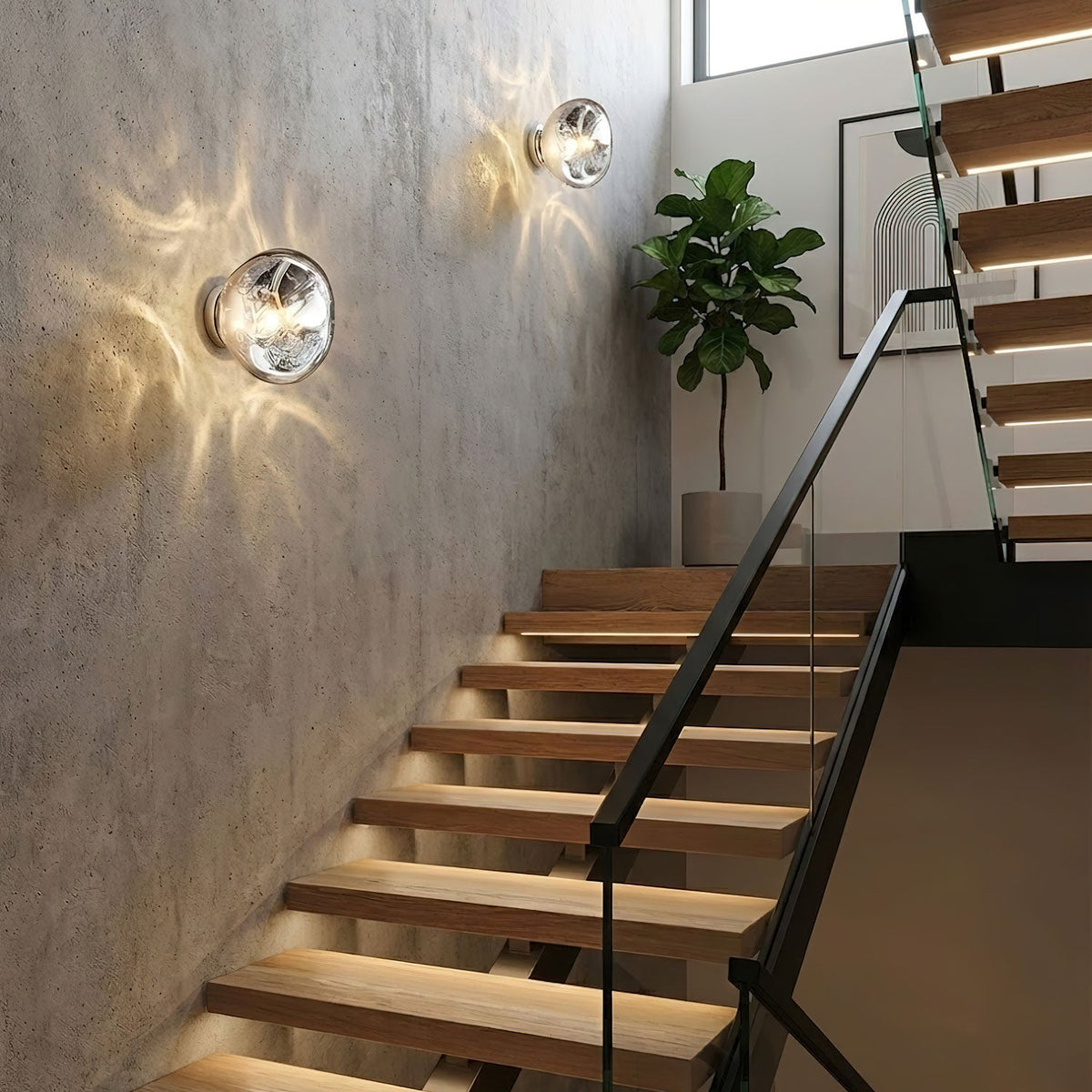 Two Clérachic wall lights with clear glass shades cast light patterns on a concrete wall beside a staircase with wooden treads.