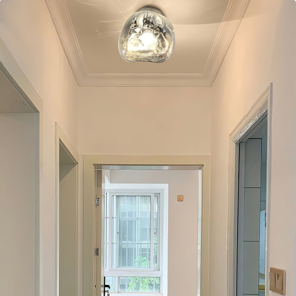 A Clérachic light mounted on the ceiling of a hallway, with a clear glass shade and a decorative plaster ceiling edge.