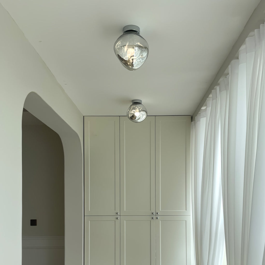 Two Clérachic ceiling lights with clear glass shades, hung along a corridor with white curtains and built-in cupboards.
