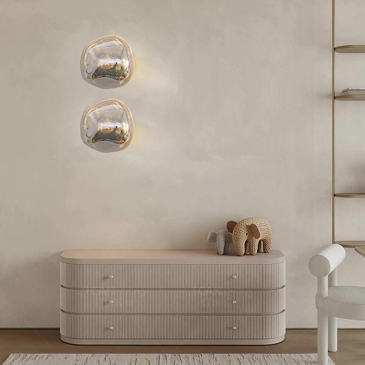 Two stacked Clérachic wall lights with clear, silver-tinted glass above a ribbed cream sideboard with a small elephant figure.