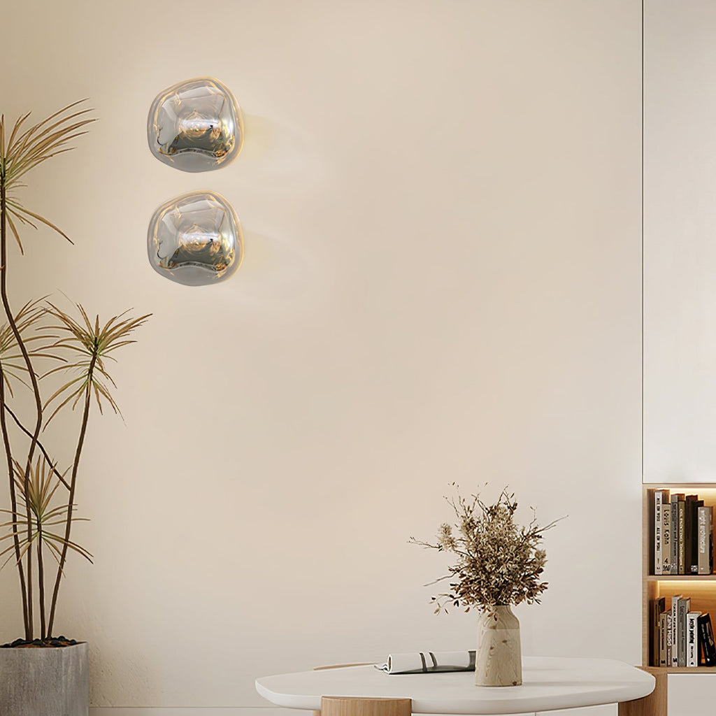 Two Clérachic wall lights with clear, silver-tinted glass beside a tall plant, with a bookcase and a round table below.
