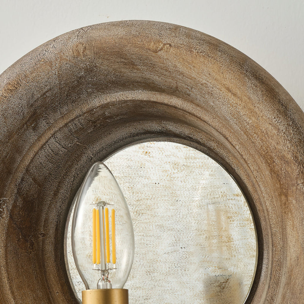 Close view of the wood surround, the aged mirror disc and a filament candle bulb on this Clérachic wall light.