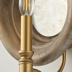 Close view of the gold candle holder with its ribbed collar, set against the wood surround of this Clérachic wall light.