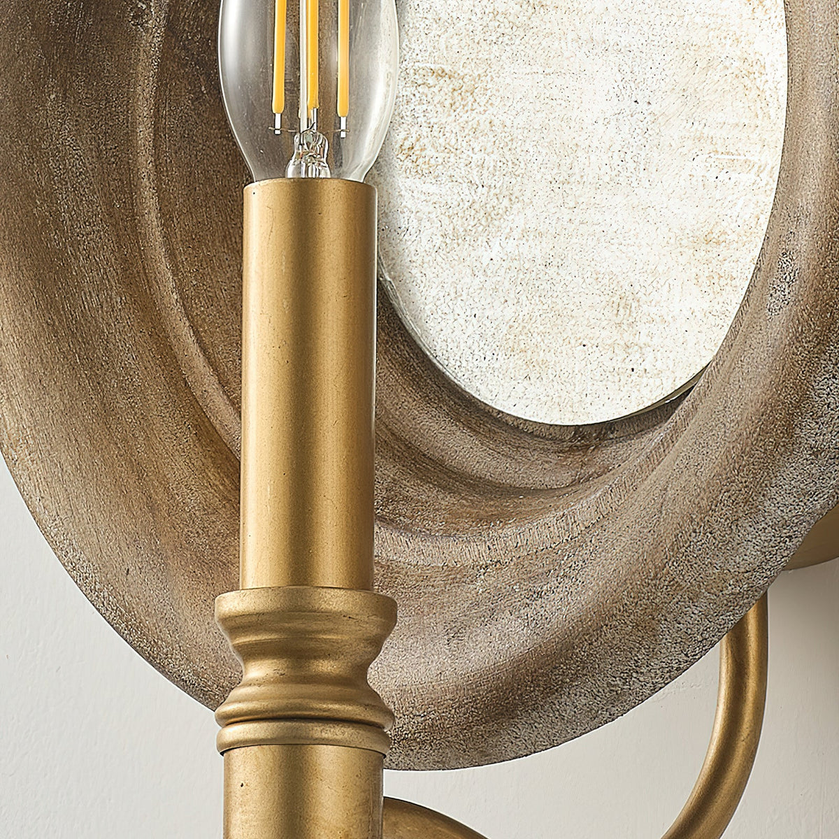 Close view of the gold candle holder with its ribbed collar, set against the wood surround of this Clérachic wall light.