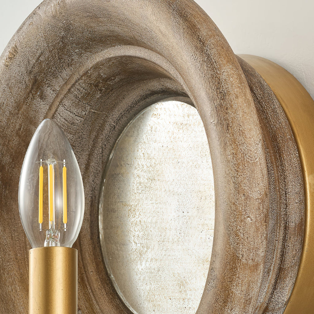 Close view of the grained wood rim, the mirror and a filament candle bulb on this Clérachic wall light.