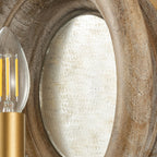 Close view of the oval mirror inside the wood surround of this Clérachic wall light, with a candle bulb at the edge.