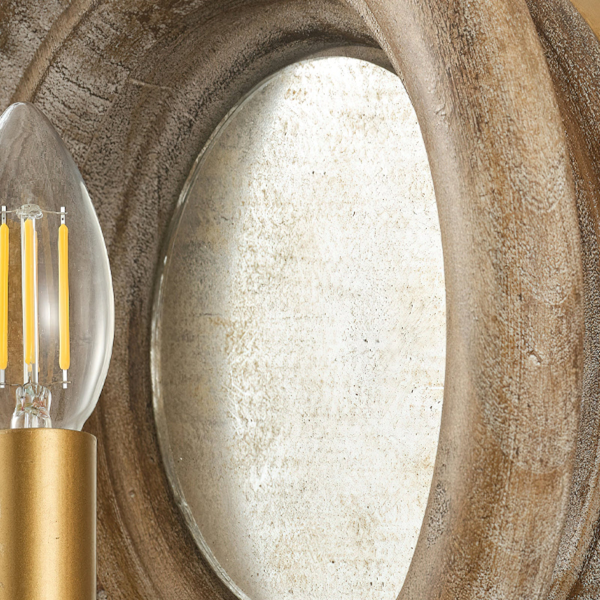 Close view of the oval mirror inside the wood surround of this Clérachic wall light, with a candle bulb at the edge.