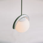 The Clérachic Citheis pendant lit from below, its hooked arm curling over the glass globe.