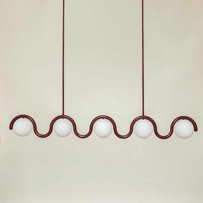 The Clérachic Citheis five-head chandelier in burgundy, wave rail spanning a cream wall.