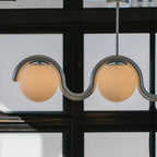 Clérachic Citheis chandelier in silver seen against black steel window frames.