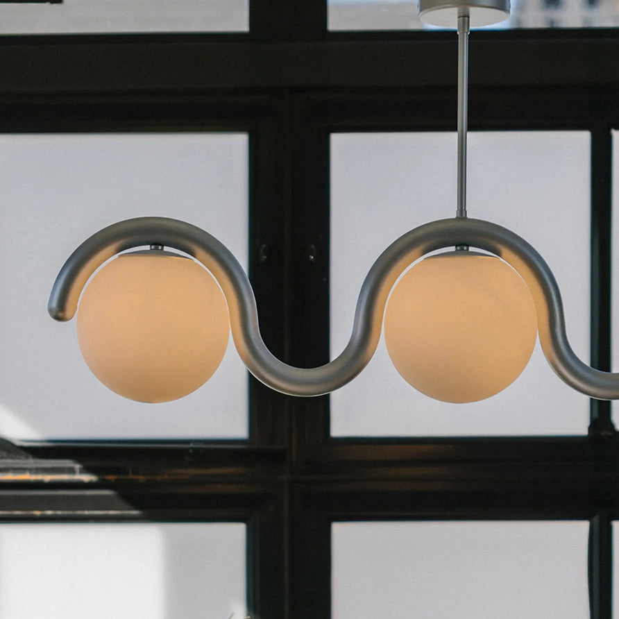 Close view of the Clérachic Citheis silver wave, two globes lit before a black window grid.