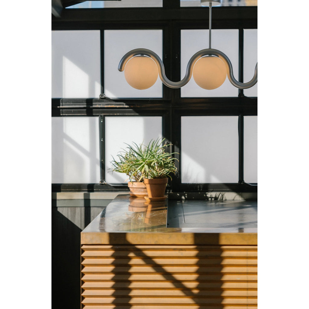 Clérachic Citheis chandelier above a kitchen island beside tall black-framed glazing.