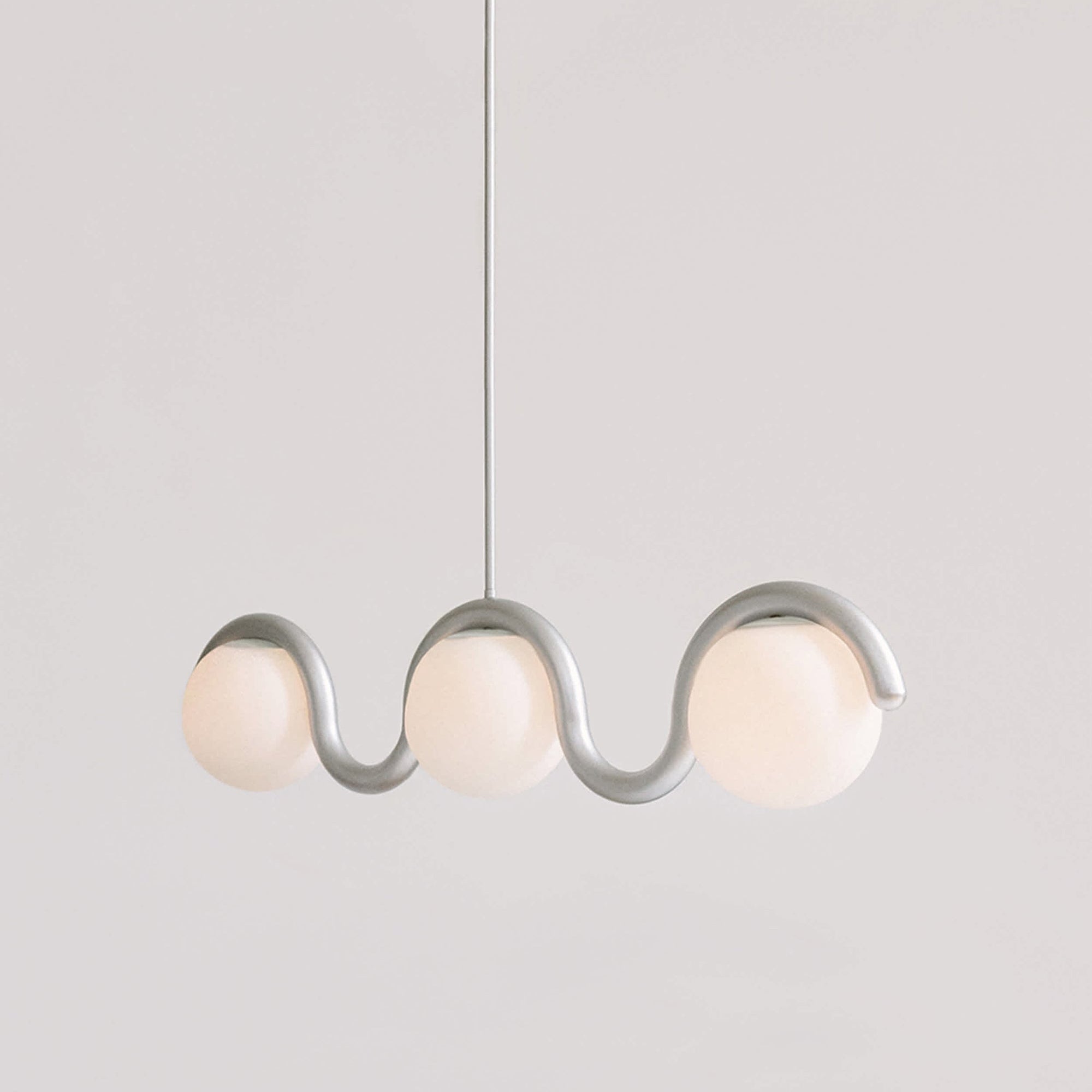 Clérachic Citheis three-head chandelier in silver, wave rail dipping between the globes.