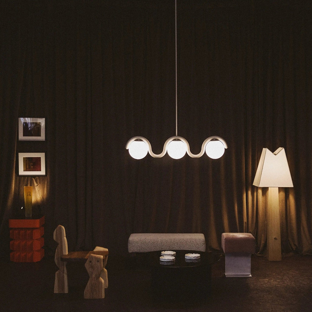 Clérachic Citheis three-head chandelier in a dark room with draped curtains and a floor lamp.