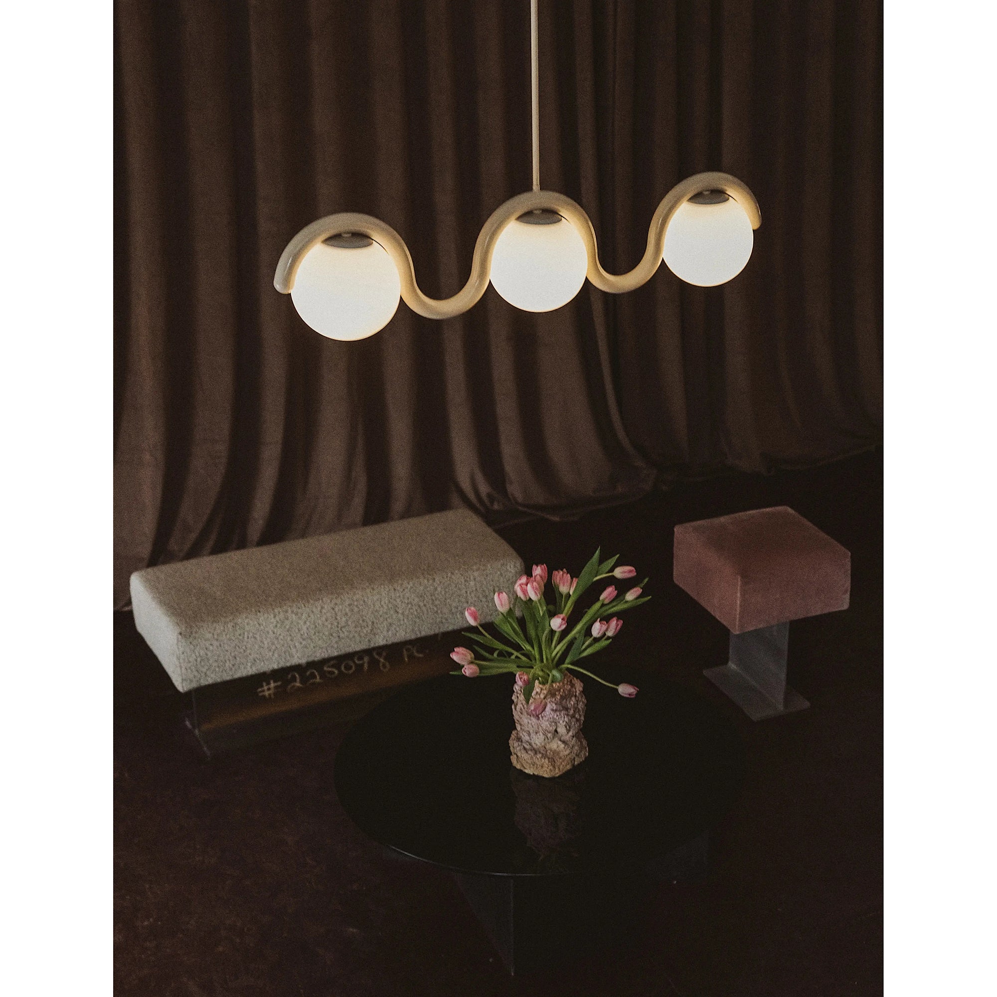 Clérachic Citheis three-head chandelier over a dark table set with tulips and a bench.