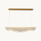 This Clérachic pendant light on a plain white backdrop, a long gold canopy bar with two fine wires holding a rippled, clear acrylic shade.