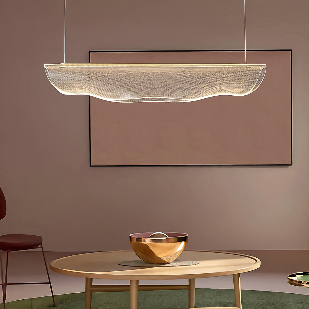 Hung over a round wooden table with a copper bowl, this Clérachic pendant light shows its wavy clear shade against a dusty-pink wall.