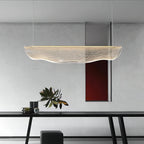 Above a black dining table with a plant and a dark stool, this Clérachic pendant light floats in front of a pale grey wall.