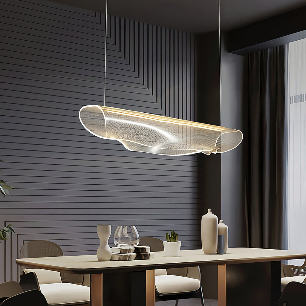 Angled view of a Clérachic pendant light over a long wooden table, set against a dark slatted wall and a heavy curtain.