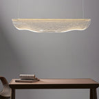 Above a wooden table with a stack of books, this Clérachic pendant light hangs in a soft grey room.