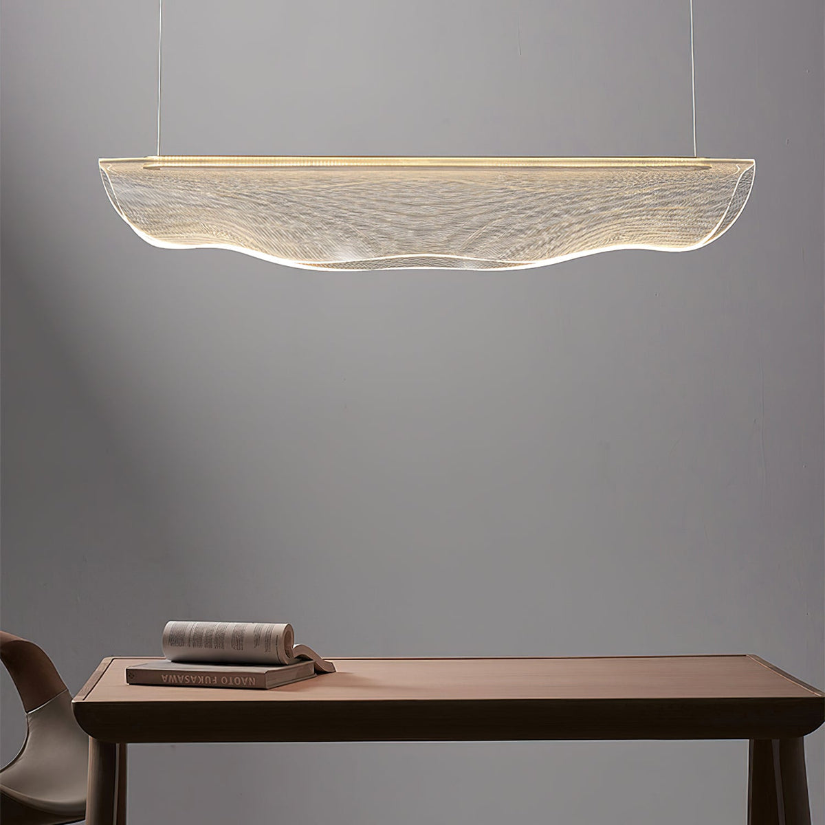 Above a wooden table with a stack of books, this Clérachic pendant light hangs in a soft grey room.