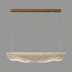 Close view of the unlit clear shade on this Clérachic pendant light, wavy at the lower edge, with gold canopy and wires above.