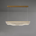 This Clérachic pendant light lit on a grey backdrop, its gold canopy bar high above the glowing, rippled shade.