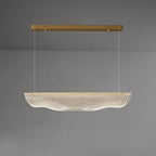This Clérachic pendant light lit on a grey backdrop, its gold canopy bar high above the glowing, rippled shade.