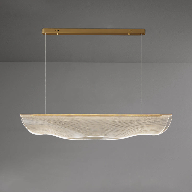 Wide view of this Clérachic pendant light lit against a grey wall, its long clear shade hung well below the gold canopy.