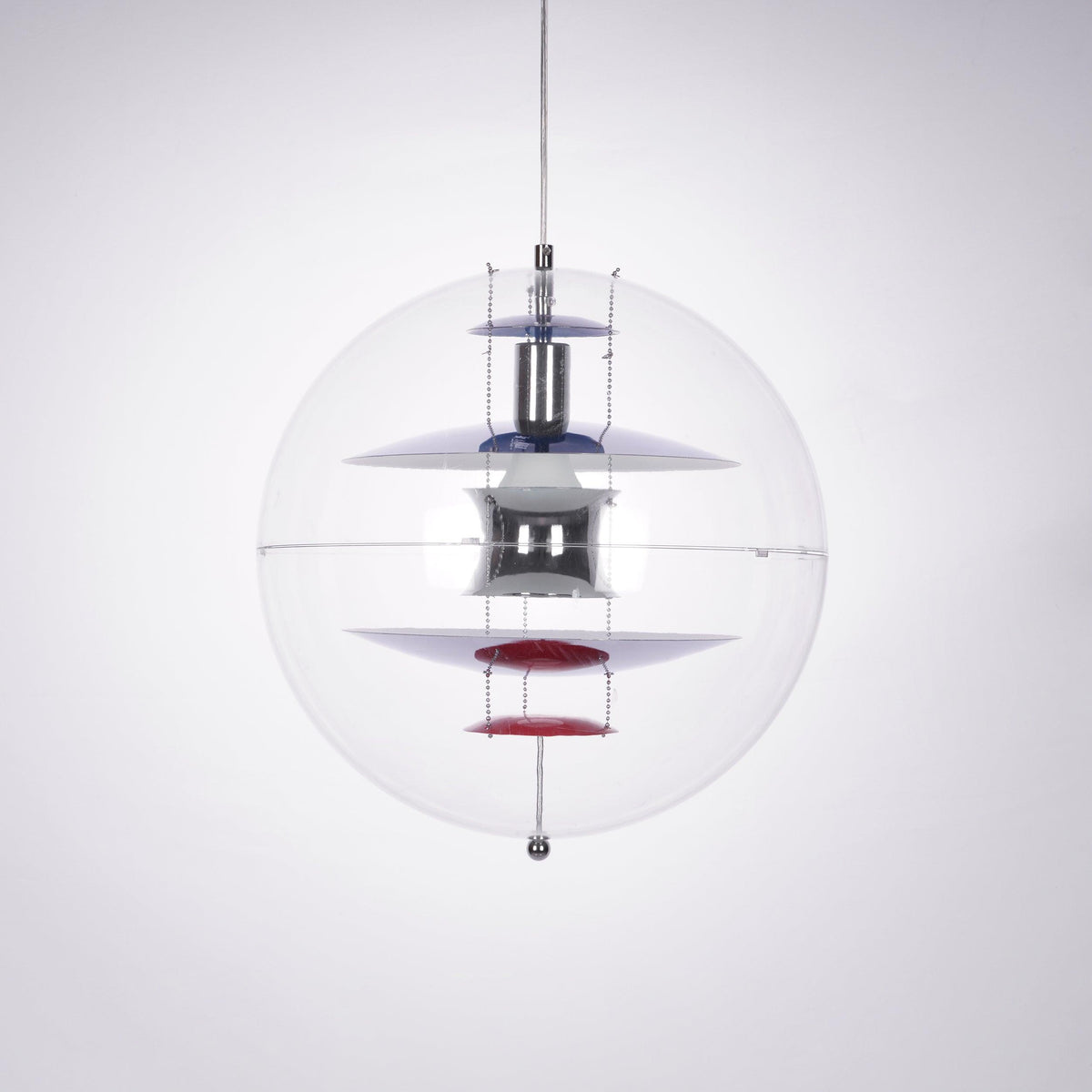 This Clérachic sphere pendant hangs on a clear cord against a soft grey-lilac backdrop, with a red dish at the base of the stack.