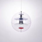 A Clérachic sphere pendant seen at a slight angle, showing chrome discs and a red dish inside the clear acrylic sphere.