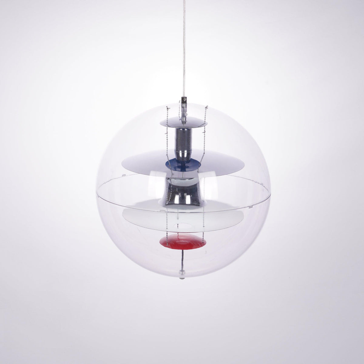 A Clérachic sphere pendant seen at a slight angle, showing chrome discs and a red dish inside the clear acrylic sphere.