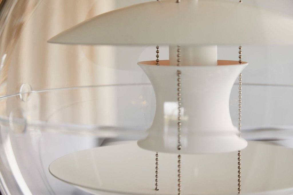 Close view of the waisted white centre piece, hanging chains and rim of the clear acrylic on this Clérachic sphere pendant.