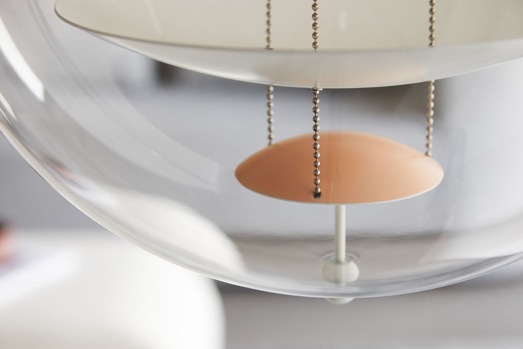 Close view of the apricot dish hanging beneath the white disc, with its chain and the curve of the acrylic on this Clérachic pendant.