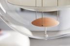 Close view of the apricot dish hanging beneath the white disc, with its chain and the curve of the acrylic on this Clérachic pendant.