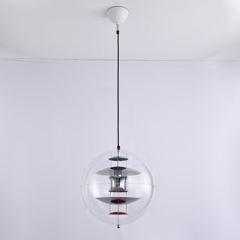 A Clérachic sphere pendant with a white ceiling canopy and black cord hangs against a pale wall, its chrome discs and red dish unlit.